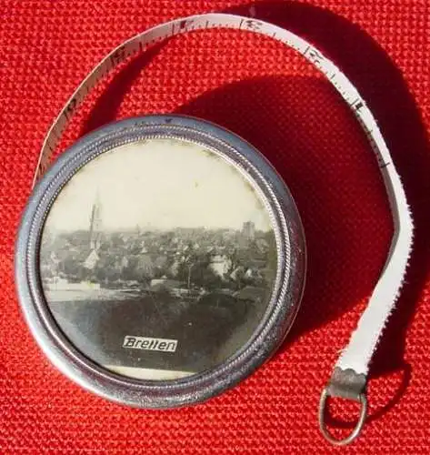 () Sehr altes Maßband, ausziehbar bis 100 cm mit Rückhol-Mechanik, in kleinem, runden Metallbehälter (Durchmesser ca. 37 mm). Mit eingelegtem Bild nebst Beschriftung 'Bretten'. Ohne Herstellerhinweis. Vermutlich um 1900 ?