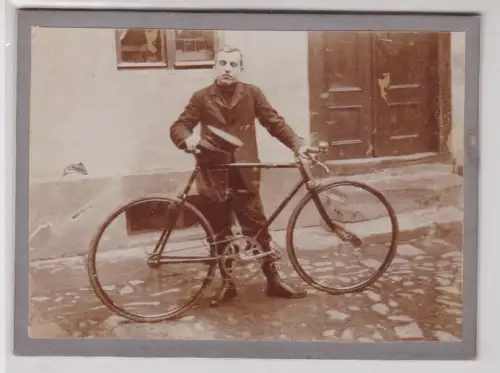 910757 Foto auf Pappe Mann mit Uniform und Schirmmütze hinter Fahrrad
