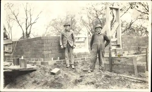 Foto Zwei Maurer vor dem Rohbau eines Hauses, Verlegen von Lochziegeln