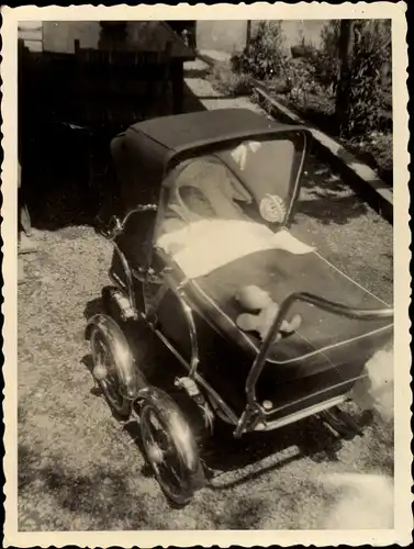 Foto Schlafendes Kleinkind in einem Kinderwagen, Teddybär