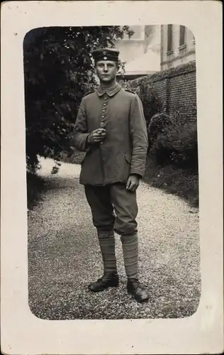 Foto Ak Junger Soldat in Uniform, Standportrait mit Zigarre, I. WK