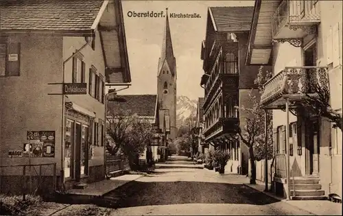 Ak Oberstdorf im Oberallgäu, Blick über die Kirchstraße auf die Kirche, Delikatessen Geschäft