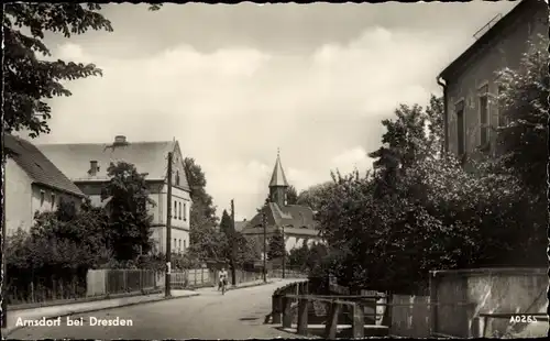 Ak Arnsdorf im Kreis Bautzen, Blick auf eine Straße im Ort, Frau auf einem Fahrrad, Kirche