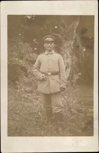 Foto Ak Deutscher Soldat in Uniform mit Zigarre, Ordenband, Stiefel