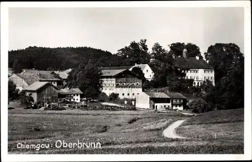 Foto Ak Oberbrunn Pittenhart im Chiemgau, Blick über ein Feld zum Ort mit Schloss, Häuser