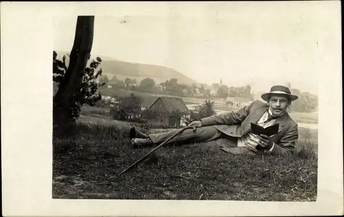 Foto Ak Wanderer beim Lesen auf einer Wiese, Hut, Gehstock