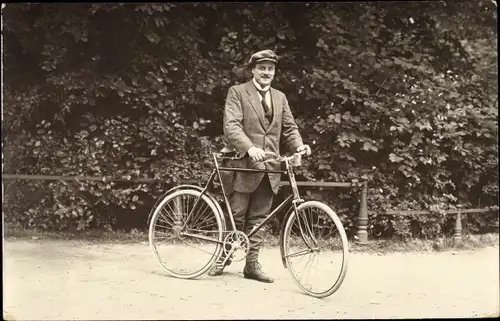 Foto Ak Mann mit einem Fahrrad, Schirmmütze