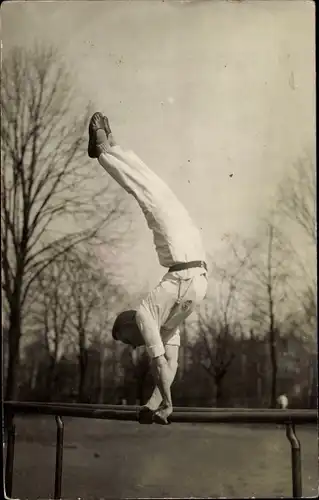 Foto Ak Turner bei einer Übung im Freien, Barren, Handstand