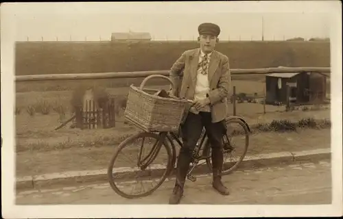 Foto Ak Radfahrer, Fahrrad, Fahrradkorb, junger Mann, Mütze