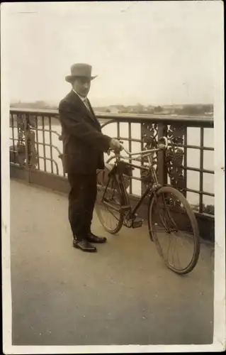 Foto Ak Mann mit Fahrrad auf einer Brücke, Brückengeländer mit Weinreben, Hut