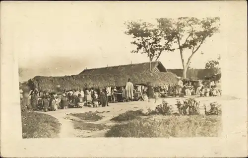 Foto Ak Afrika, Dorfbewohner vor einer Hütte, Essenszubereitung