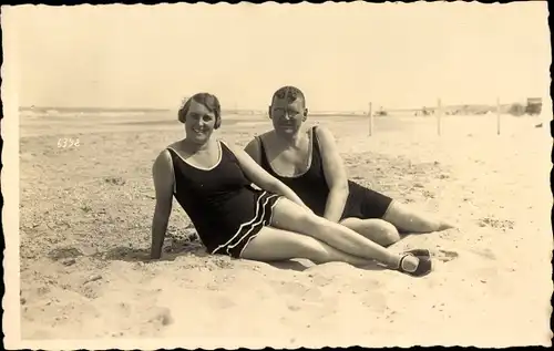 Foto Ak Mann und Frau in Badeanzügen am Strand im Sand liegend
