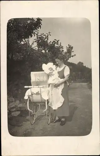 Foto Ak Frau mit Baby im Arm neben einem Kinderwagen