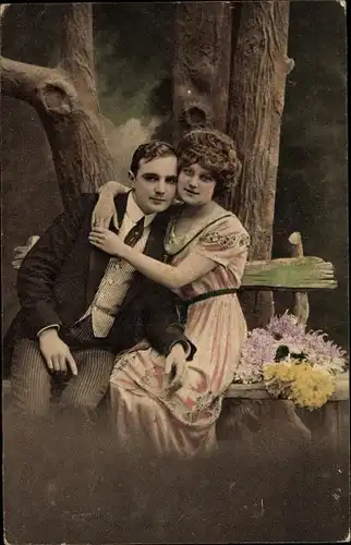Ak Liebespaar, Umarmung auf einer Sitzbank, Blumen