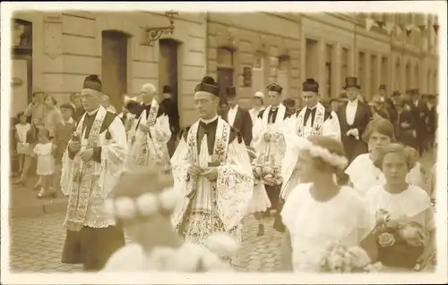 Foto Ak Kirchenfest, Geistliche auf der Straße, Frauen mit Blumen