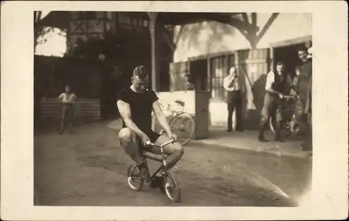 Foto Ak Mann auf einem kleinen Kinderfahrrad