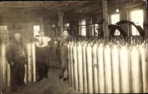 Foto Ak Drei Männer mit großen Gasflaschen in einer Halle