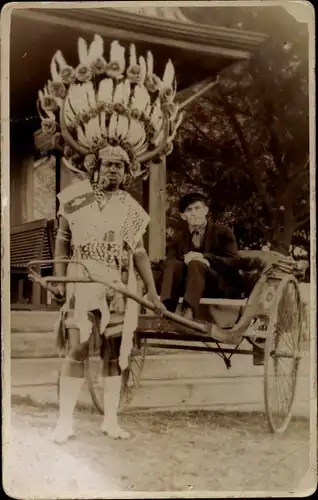 Foto Ak Asien ?, Ozeanien ?, Rikschafahrer in volkstypischer Kleidung, Kopfschmuck
