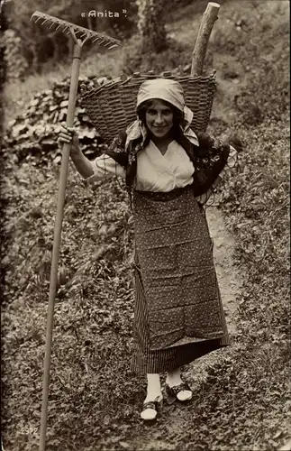 Ak Junge Frau in schweizerischer Tracht mit Harke, Korb voller Holz