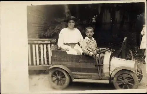 Foto Ak Junge und Frau in einem Auto, Spielzaugauto, Seifenkiste