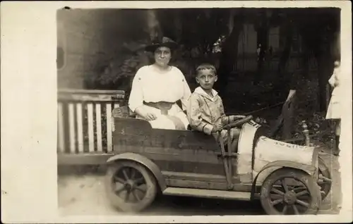 Foto Ak Junge und Frau in einem Automobil, Spielzeugauto, Seifenkiste