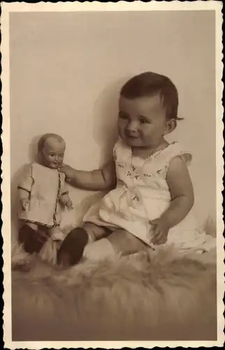Foto Ak Mädchen mit Puppe auf einem Fell sitzend, Portrait