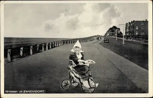 Ak Zandvoort Nordholland, Kind in typischer Tracht auf einem Dreirad, Fotomontage