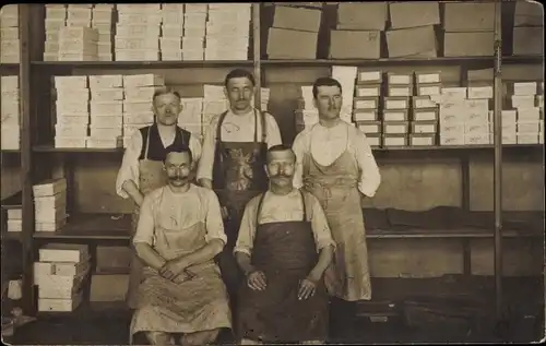 Foto Ak Handwerker mit Arbeitsschürzen in einem Warenlager, Regal mit Kartons