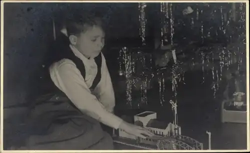 Foto Ak Junge mit Spielzeugeisenbahn unterm Tannenbaum