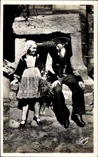 Ak Junge und Mädchen in bretonischen Trachten am Brunnen