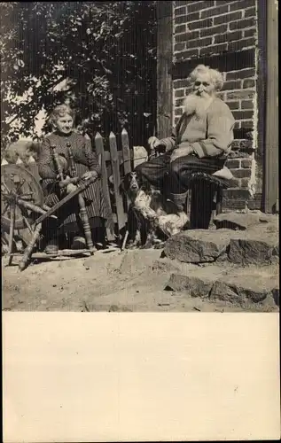 Foto Ak Bärtiger Mann mit Hund, alte Frau am Spinnrad