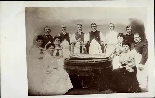 Foto Ak Köche und Frauen am Tisch, Fischfilet, Kochen, Küchenschürze, Gruppenbild