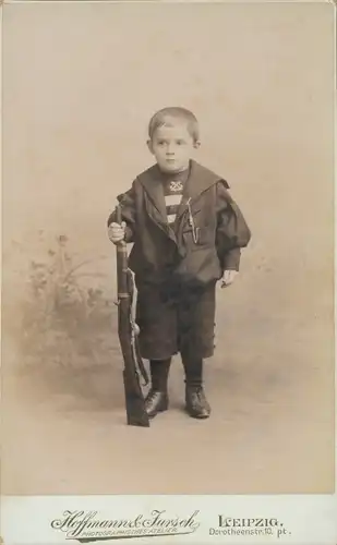Foto Kleiner Junge mit Spielzeuggewehr, Standportrait im Atelier