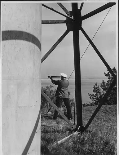 Foto Lotse mit Fernrohr vor einem Leuchtturm, Lotsendorf, Fotograf Hilde Zenker, Berlin