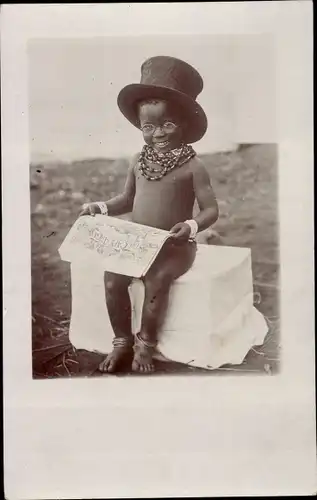 Foto Ak Kleiner farbiger Junge mit Zylinder und Zeitung