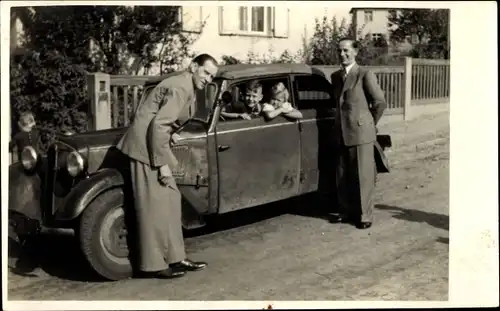 Foto Kinder in einem Automobil, Männer in Anzügen davor