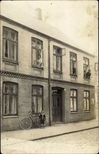 Foto Ak Junge mit Fahrrad vor einem Wohnhaus, Anwohner an den Fenstern