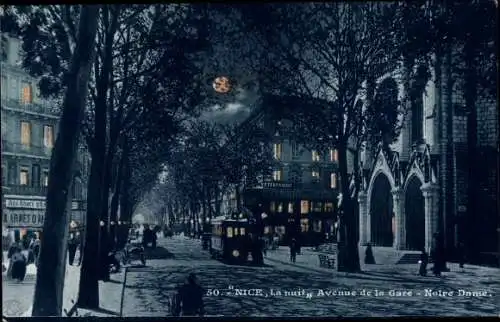 Ak Nice Nizza Alpes Maritimes, L'Avenue de la Gare, Straßenbahn, Notre Dame, Nachtansicht