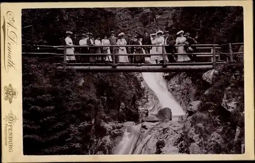 Kabinettfoto Personen auf einem Steg vor einem Wasserfall