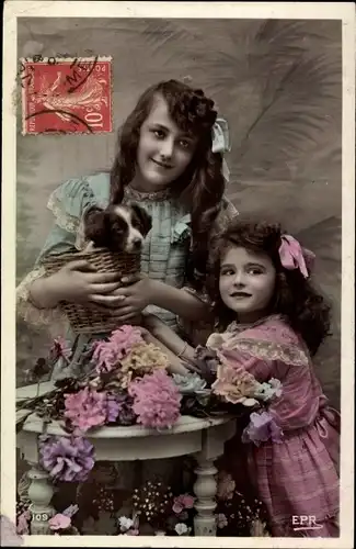 Ak Zwei Mädchen mit Hundewelpen in einem Korb, Blumen