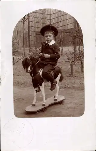 Foto Ak Junge im Matrosenanzug auf Spielzeugpferd auf Rollen, Schaukelpferd