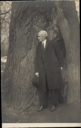 Foto Ak Mann im Mantel vor einem Baum, Portrait