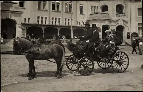 Foto Ak Geschmückte Kutsche vor einem Gebäude, Kutscher, Fahrgäste, Pferde