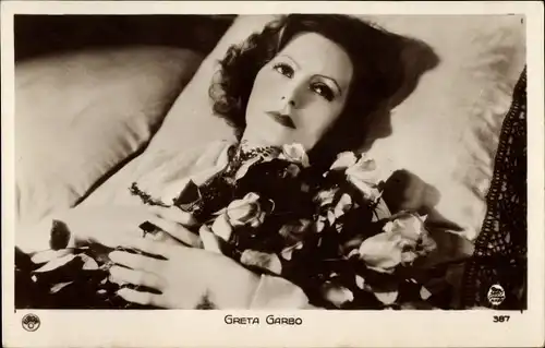 Ak Schauspielerin Greta Garbo, Bett, Kissen, Blumen