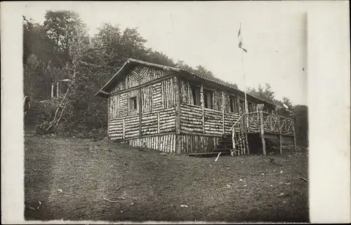 Foto Ak Verdun Meuse, von Mannschaften erbaute Offizierswohnung im Waldlager, Kaiserliche Fahne