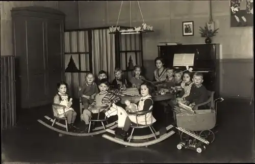 Foto Ak Kinder mit Schaukelpferden und Puppenwagen, Spielzeugfeuerwehr, Klavier, Erzieherin