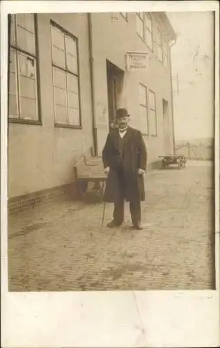 Foto Ak Nordseebad Cuxhaven, Mann im Mantel mit Melone vor einem Gebäude