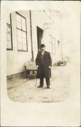 Foto Ak Nordseebad Cuxhaven, Mann im Mantel mit Melone vor einem Gebäude