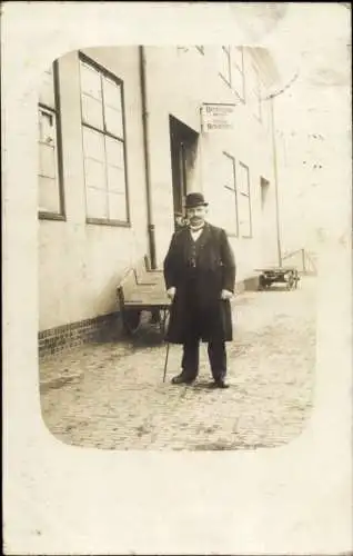 Foto Ak Nordseebad Cuxhaven, Mann im Mantel mit Melone vor einem Gebäude