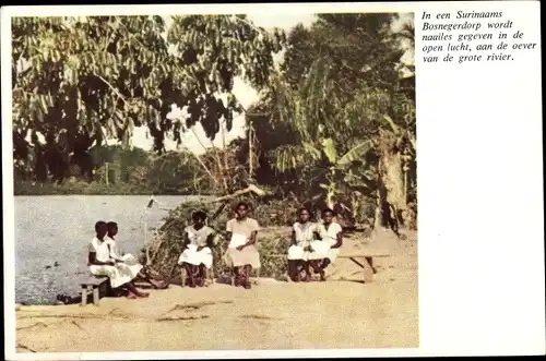 Ak Suriname, In een Bosnegerdorp wordt naailes gegeven in de open lucht, aan de oever van de grote.